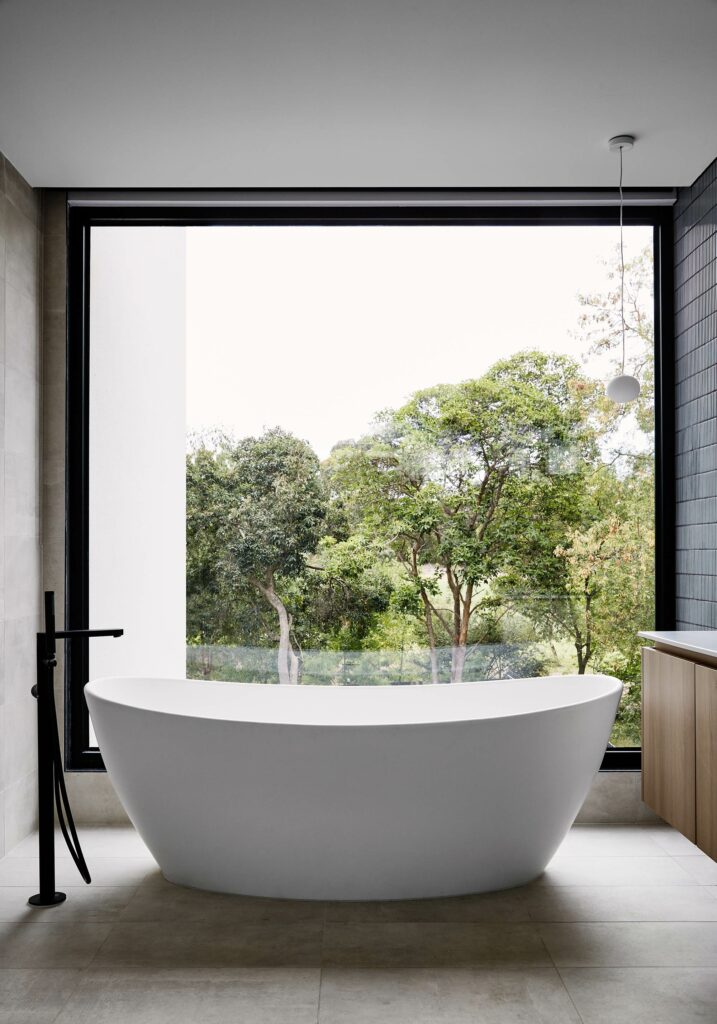 Maike Design bathroom. Large window and freestanding bath. Beautiful view of trees.