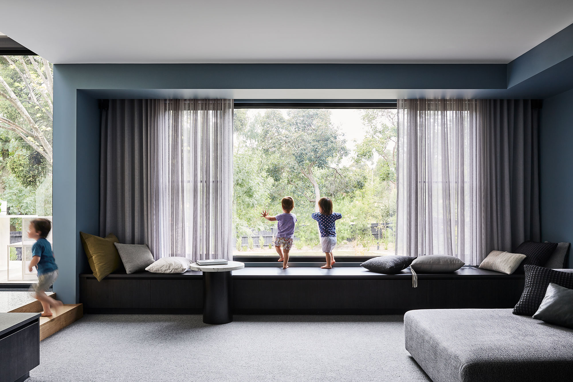 Maike Design lounge room. Bench steat and sheer curtains. Blue painted walls