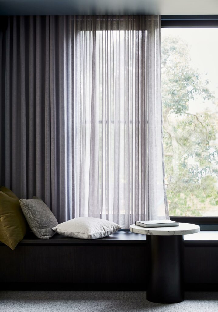 Maike Design lounge room. Bench steat and sheer curtains. Blue painted walls. Marble side table